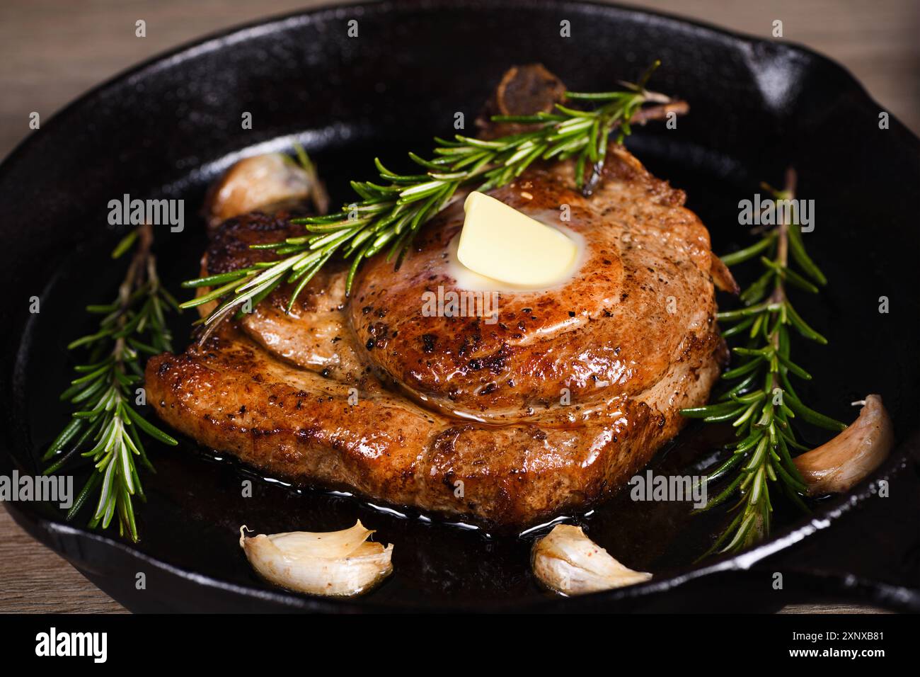 Schweinekotelett auf dem Knochen in einem Stück Butter mit Knoblauch ...