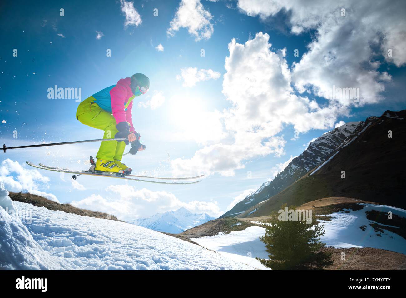 Mädchen im Flug, nachdem sie im Frühjahr vor der Kulisse der Berge und des blauen Himmels von einem Kicker gesprungen sind. Nahaufnahme Weitwinkel. Das Konzept von Stockfoto