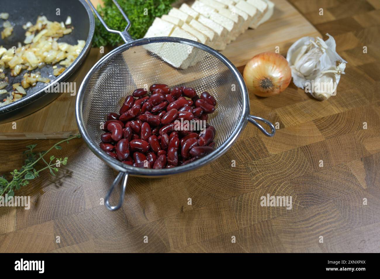Kidneybohnen und Tofu, Zwiebeln und Kräuter, vegane Proteinquellen und Zutaten für ein gesundes Gericht wie Dip oder Aufstrich, hölzerner Küchentisch, Kopierraum, Stockfoto