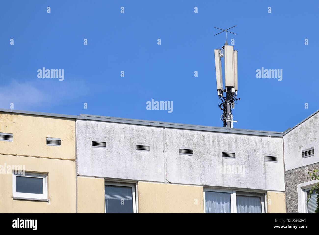 Mobilfunk-Basisstation-Antenne auf dem Telekommunikationsmast für die Mobilkommunikation auf dem Dach eines Mehrfamilienhochhauses gegen a b Stockfoto