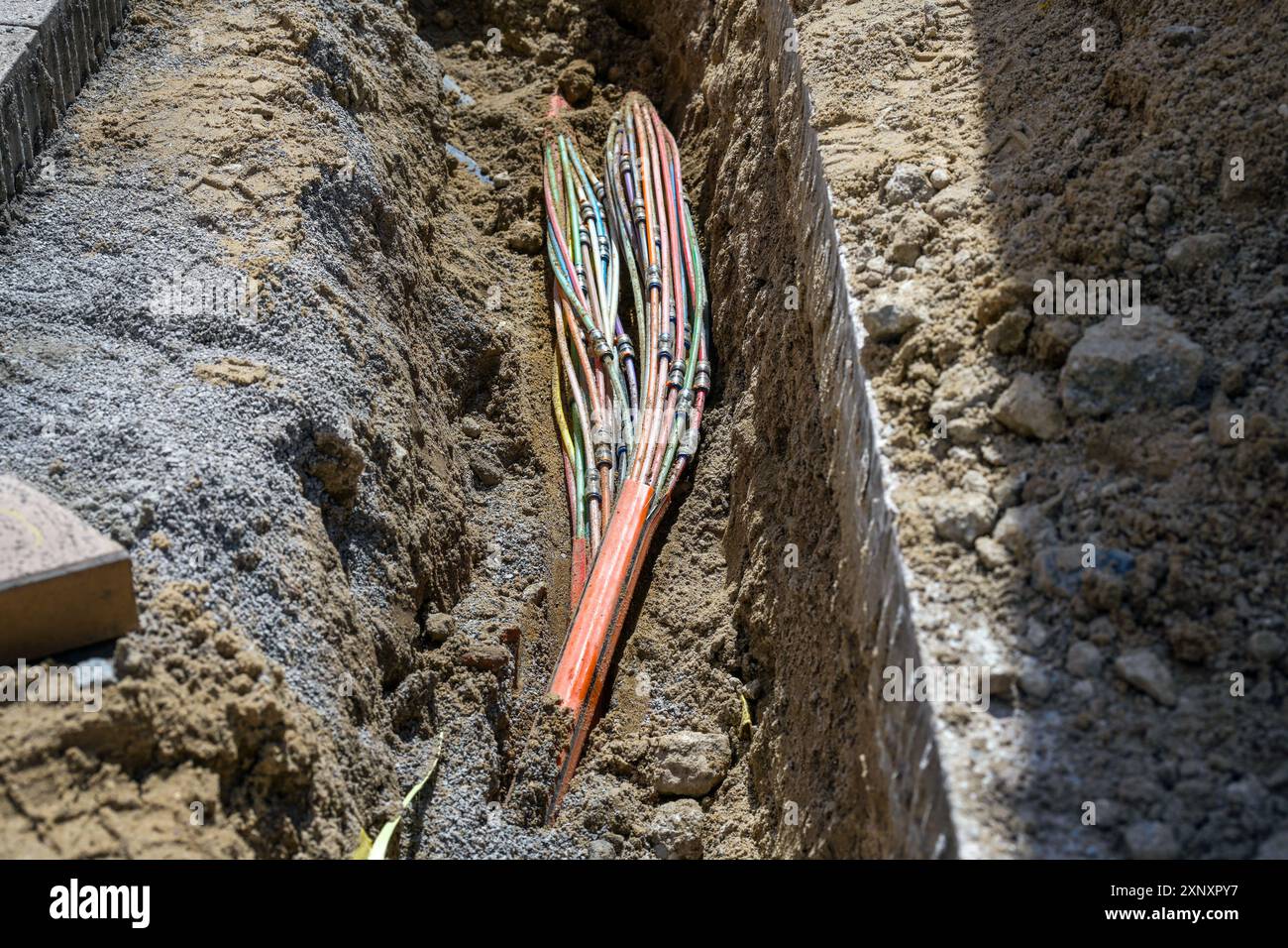 Erdkabel mit mehreren Lichtwellenleitern in einem Graben im Gehsteig verlegt, Kommunikations- und Infrastrukturkonzept, Kopierraum, auswählen Stockfoto