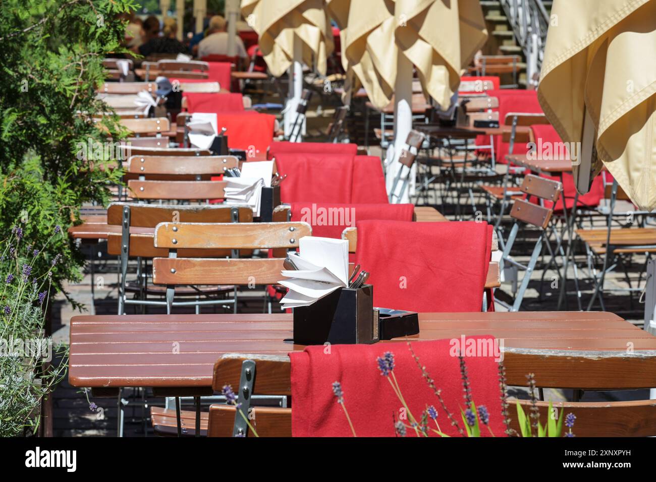 Einladende rustikale Möbel in einem Straßenrestaurant oder Café mit Holztischen und -Stühlen und roten Decken, Outdoor Gastronomie, ausgewählte Fokussierung, schmales de Stockfoto