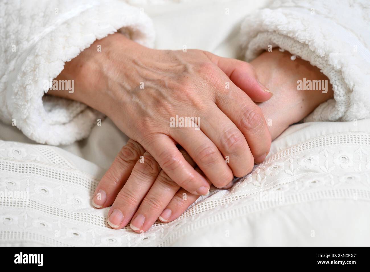 Nahaufnahme der Hände einer alten Frau, die eine übereinander gefaltet hat. Ältere Frau mit gefalteten Händen Stockfoto