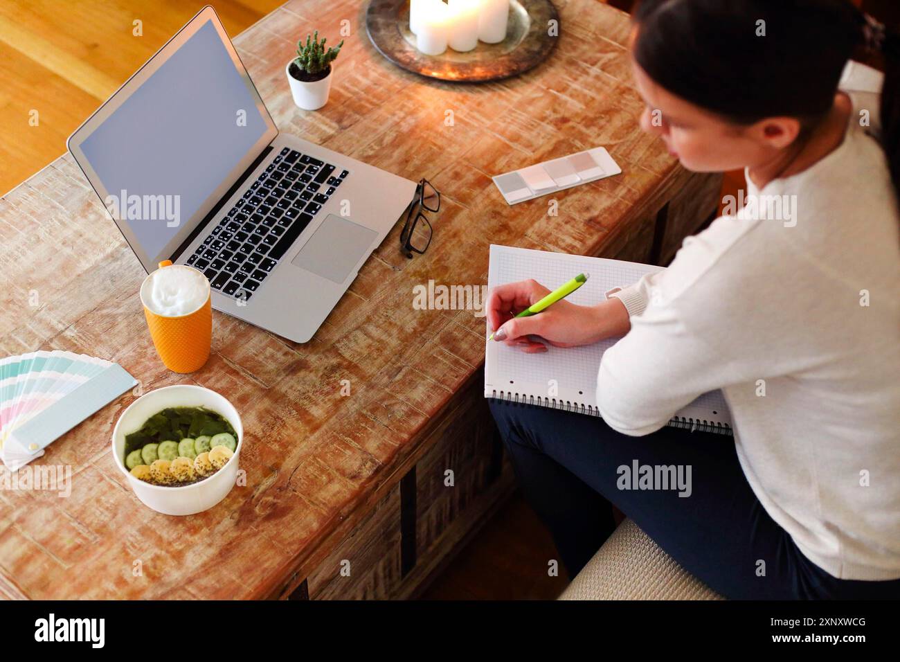 Glückliche Frau in lässiger Kleidung sitzt auf der Couch und Surfen Smartphone während der Arbeit an Remote-Projekt zu Hause Stockfoto