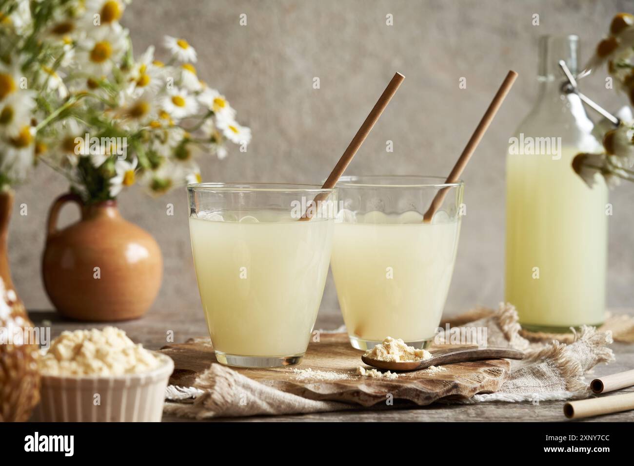 Zwei Gläser und eine Flasche frische Molke mit Papierhalmen auf einem Tisch Stockfoto