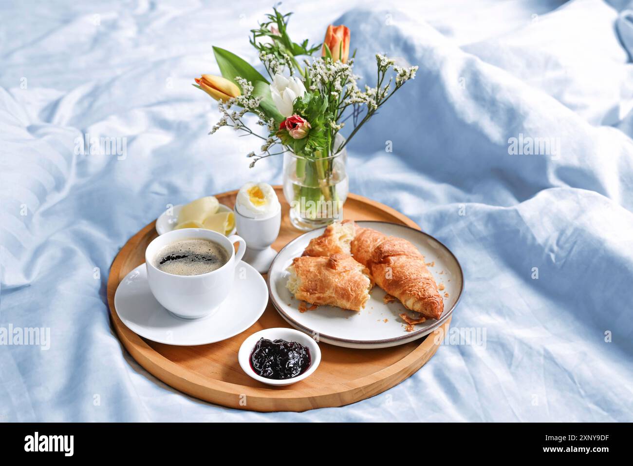 Happy Morning mit Frühstück im Bett, Blumen, Croissants, Kaffee und mehr auf einem Tablett auf blauweißer Bettwäsche zum Geburtstag, Valentinstag oder Muttertag, Kopie Stockfoto