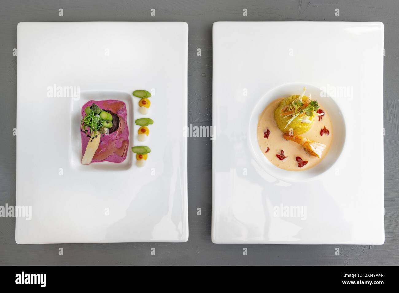 Zwei Gänge eines modernen Gourmetmenüs auf weißen Tellern, Spargel in Nori-Blatt mit Rote-Bete-Sauce, Safranrisotto mit Garnelen und Krustentiersauce Stockfoto