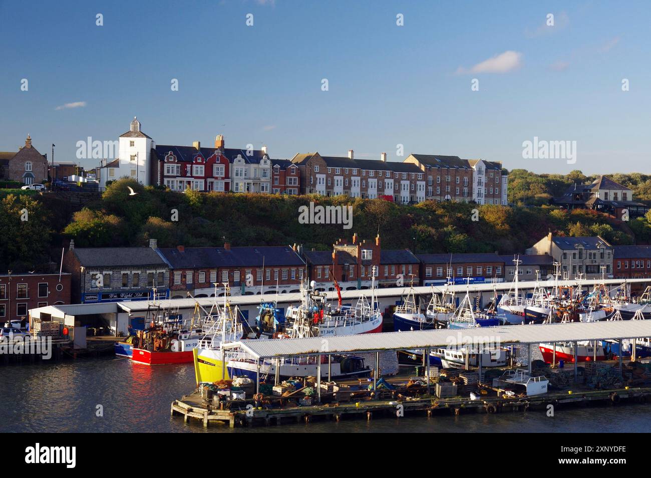 Hafen bei Sonnenuntergang mit Booten, Häusern auf einem Hügel und Wasser im Vordergrund, Fischerboote, Tynemouth, England, Großbritannien Stockfoto