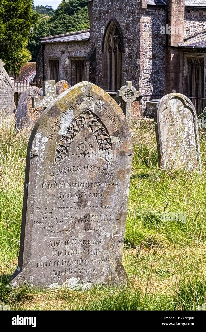 Aldbourne / England - 25. Juni 2024: Alte, verwitterte Steingräber zieren am 25. Juni 2024 einen mittelalterlichen Kirchenfriedhof in Aldbourne, England. Stockfoto