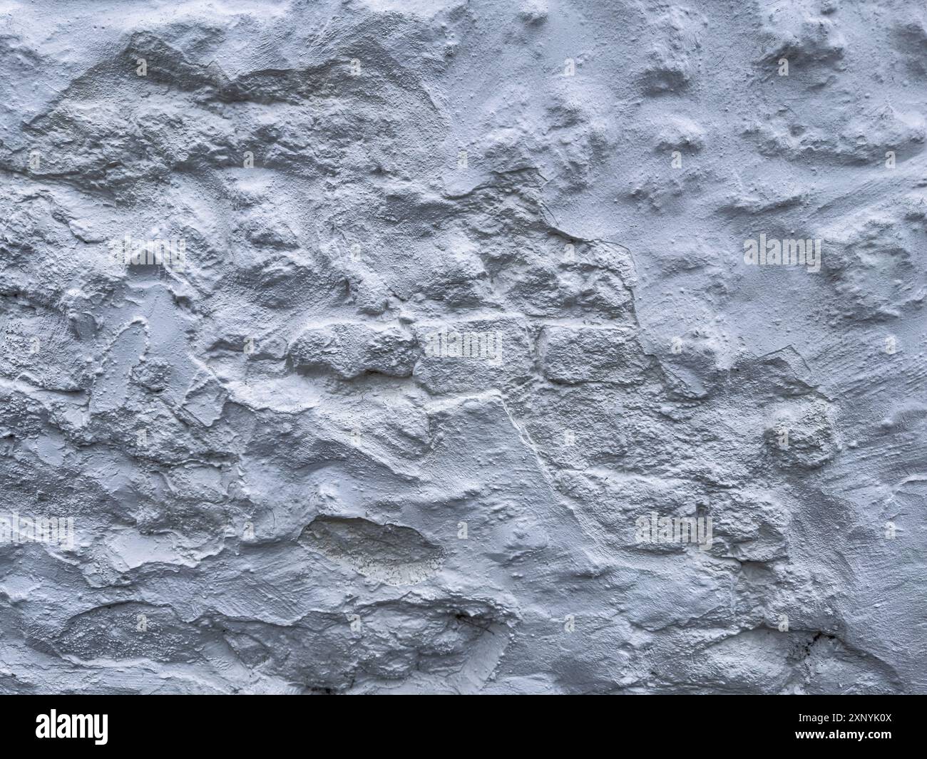 Eine alte weiße Steinmauer an einem Gebäude in der englischen Landschaft schafft ein interessantes strukturiertes grafisches Element, das als Hintergrundplatte verwendet werden kann. Stockfoto