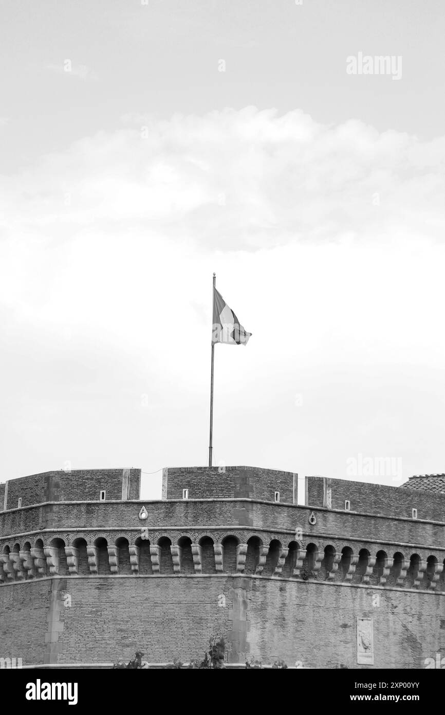 Italienische Flagge weht im Wind an der Spitze der Festung und des Schlossgebäudes im Parco Adriano in Schwarz-weiß von Castel Sant'Angelo (Mausoleum von Hadrian) Stockfoto