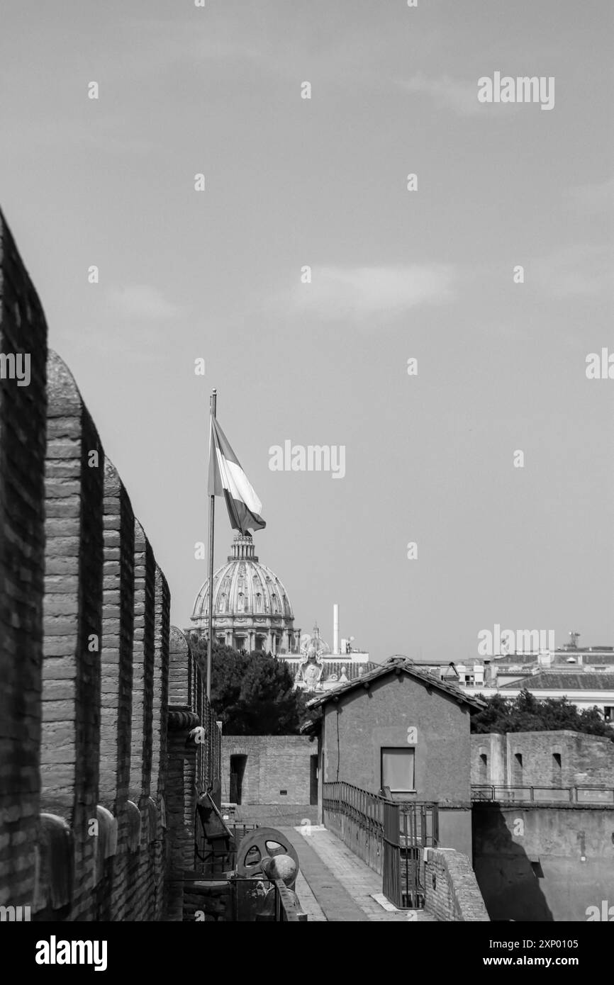 Petersdom in der Vatikanstadt, vom Castel Sant'Angelo Museum aus gesehen, wie die italienische Flagge im Wind in Schwarz-weiß geöffnet ist Stockfoto