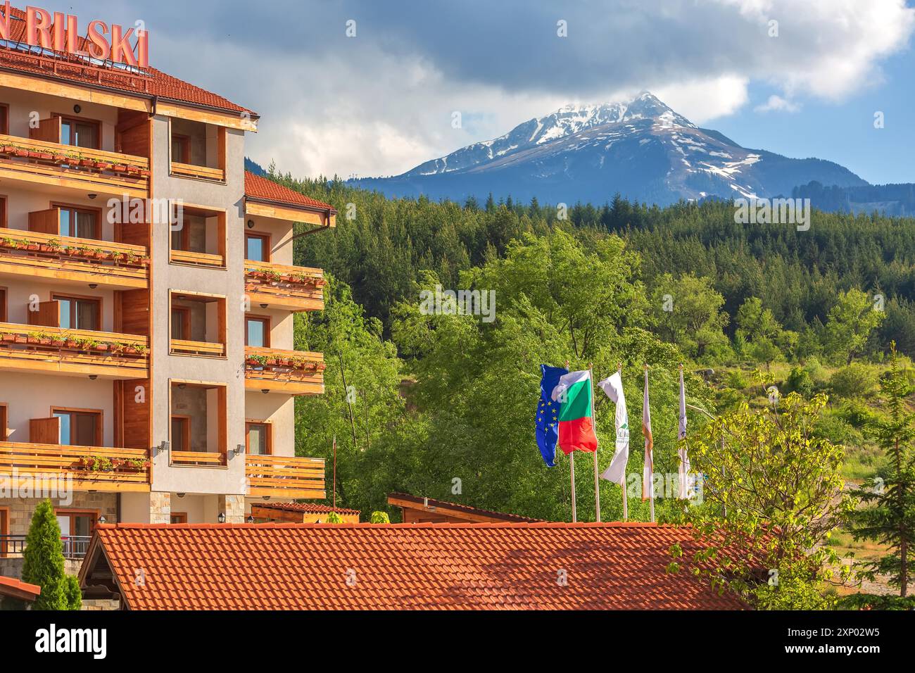 Bulgarien, Bansko, 5. Mai 2020: Hotel St. Ivan Rilski Flags, grüner Wald und Blick auf den Todorka-Berg Stockfoto