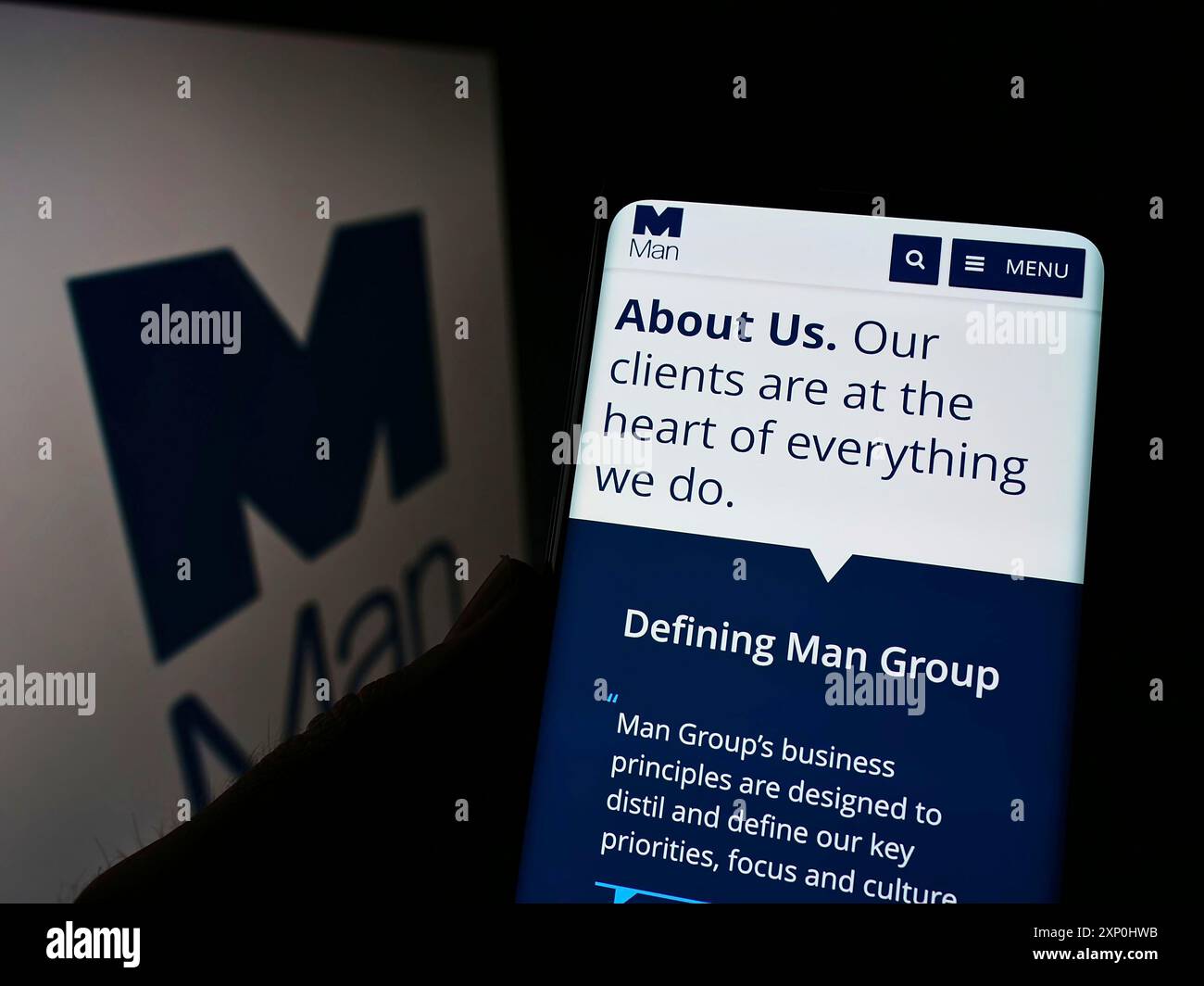 Stuttgart, Deutschland, 02.06.2022: Person, die ein Handy hält, mit Webseite der britischen man Group plc vor dem Logo auf dem Bildschirm. Konzentrieren Sie sich auf Stockfoto