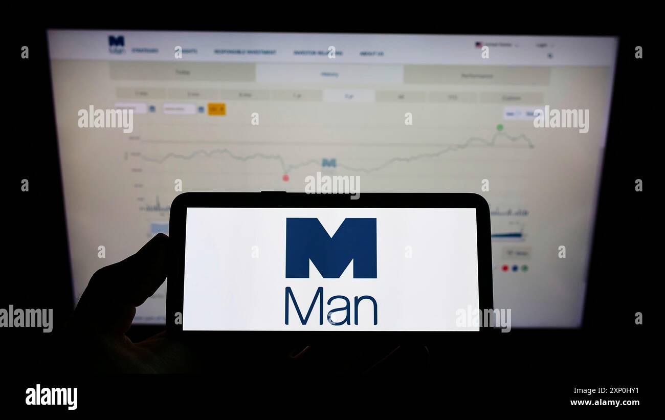 Stuttgart, Deutschland, 02.06.2022: Person, die ein Mobiltelefon mit dem Logo der britischen Finanzgesellschaft man Group plc auf dem Bildschirm vor dem Business Web hält Stockfoto