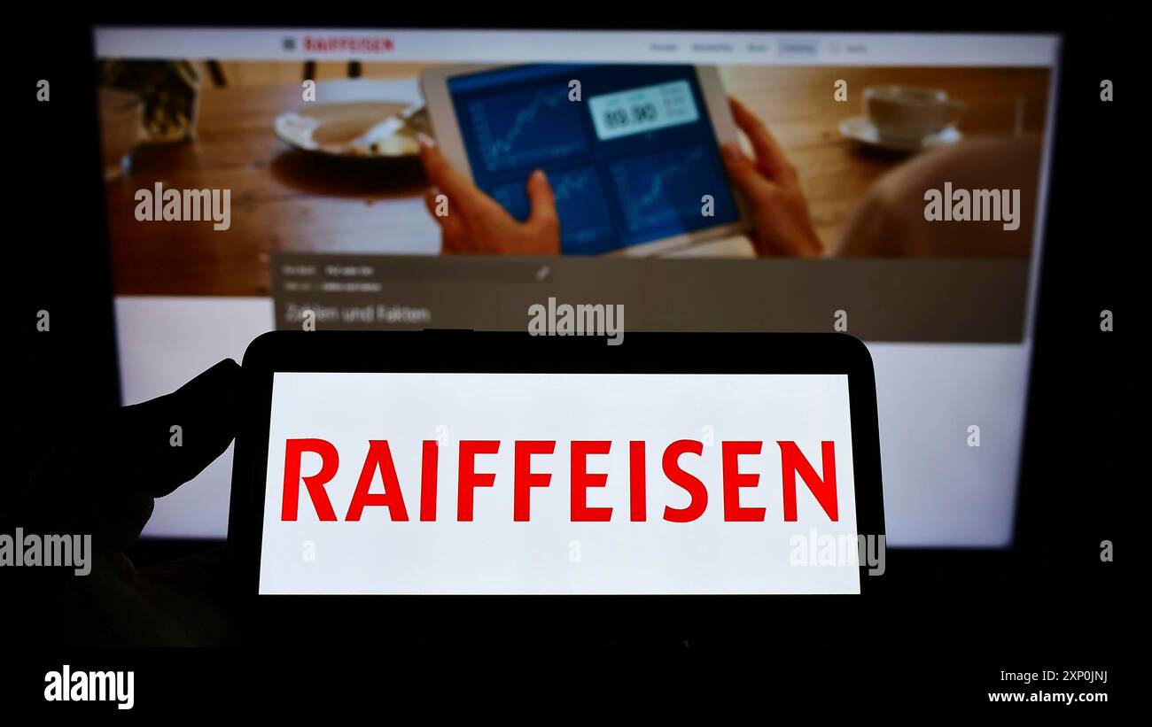 Stuttgart, Deutschland, 29.01.2022: Handybesitzer mit Logo der Schweizer Bank Raiffeisen Schweiz Genossenschaft auf dem Bildschirm vor der Webseite. Stockfoto