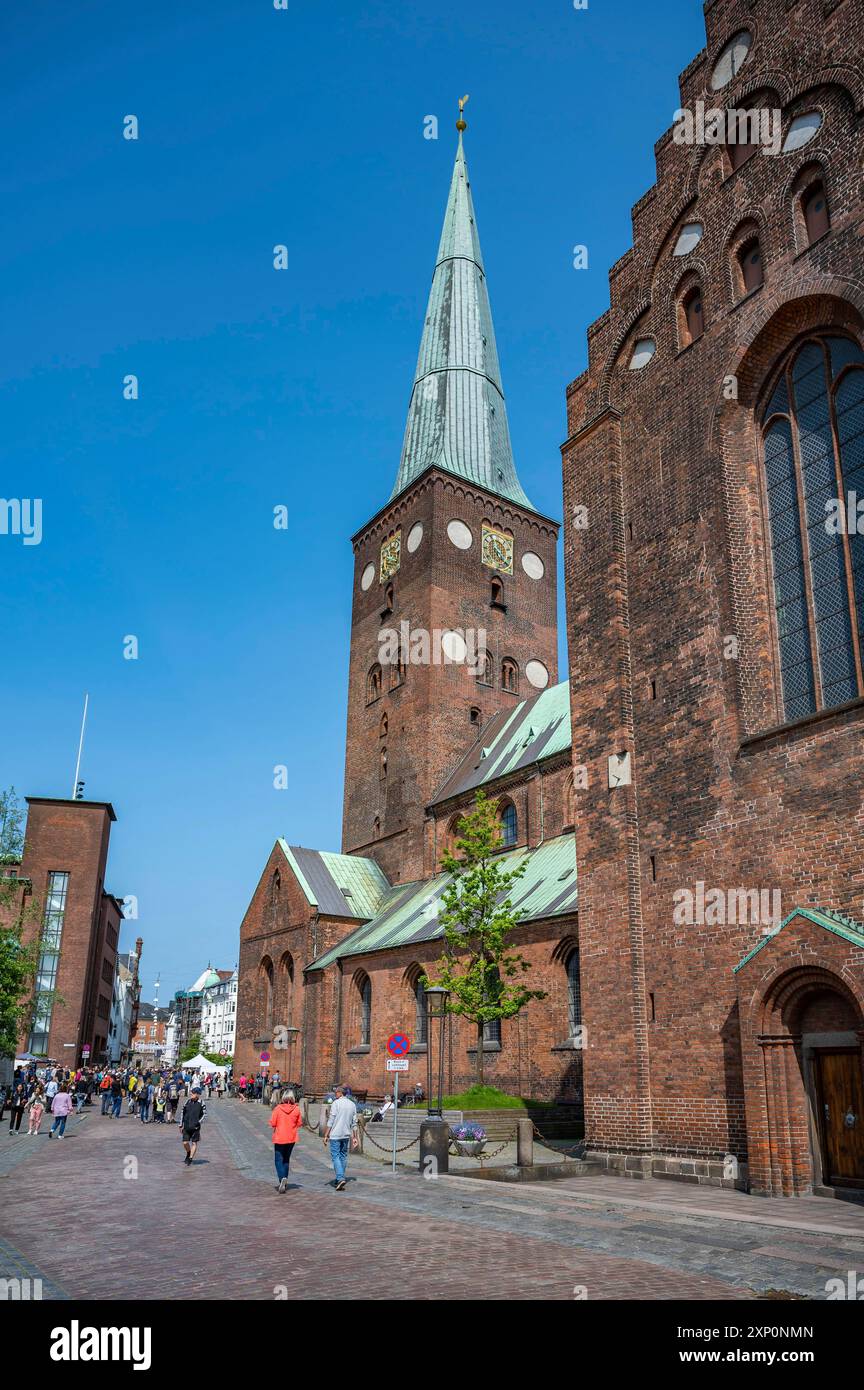 Kirchturm der Kathedrale von Aarhus mit Leuten, die bei schönem Wetter vor der Tür laufen, vertikale Aufnahme Stockfoto