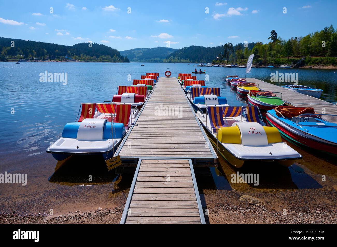 Eine malerische Szene mit bunten Tretbooten und Holzbooten auf einem Bootssteg vor dem Schluchsee, umgeben von Bergen, Frühling, Schluchsee Stockfoto