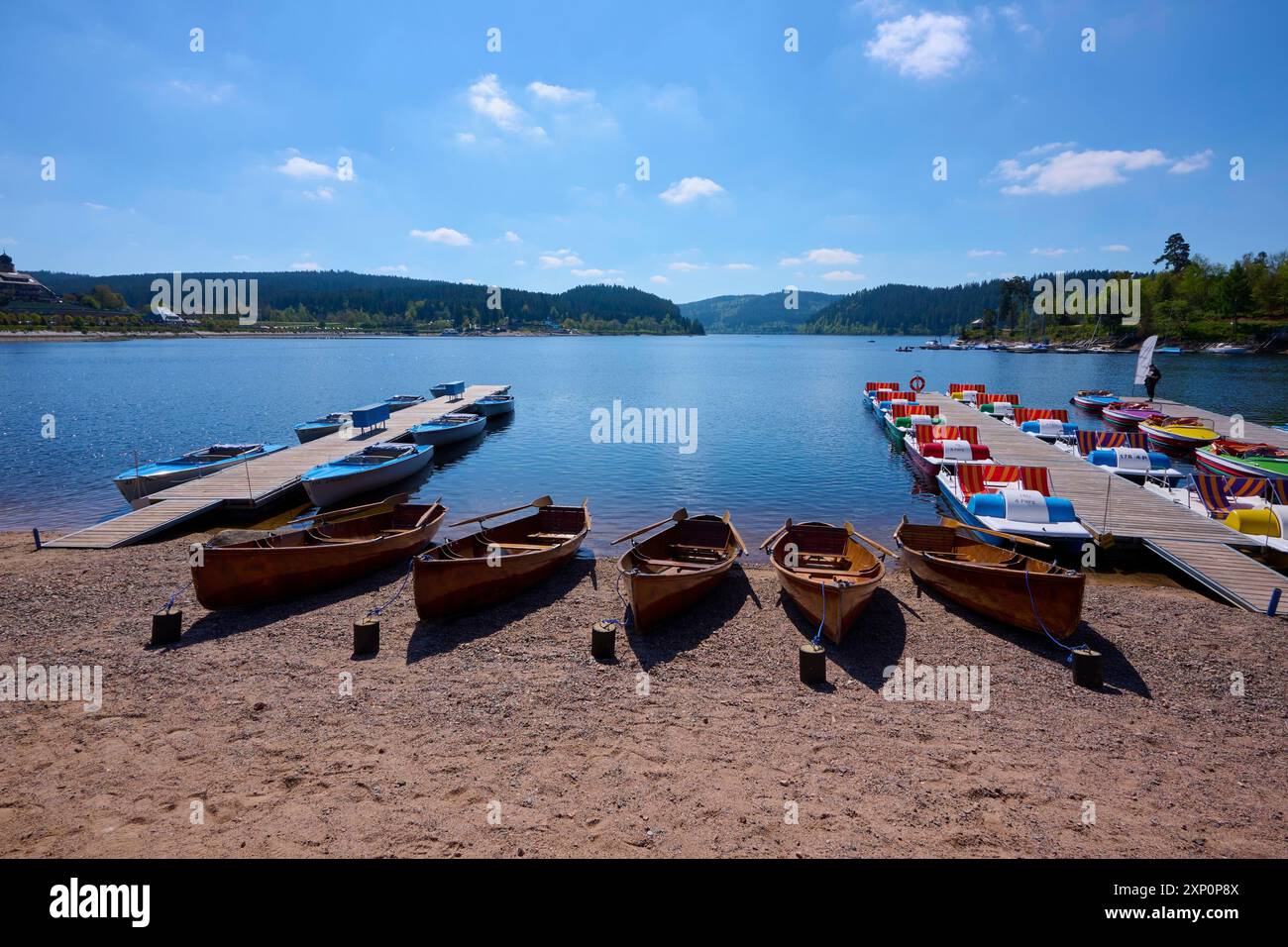 Eine malerische Szene mit bunten Tretbooten und Holzbooten auf einem Bootssteg vor dem Schluchsee, umgeben von Bergen, Frühling, Schluchsee Stockfoto