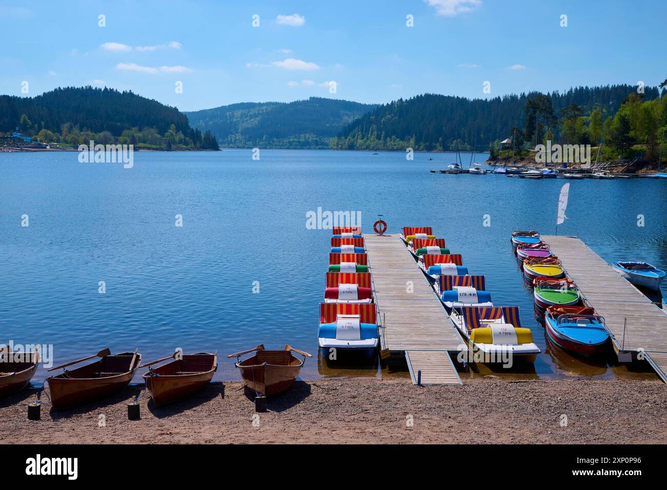 Eine malerische Szene mit bunten Tretbooten und Holzbooten auf einem Bootssteg vor dem Schluchsee, umgeben von Bergen, Frühling, Schluchsee Stockfoto