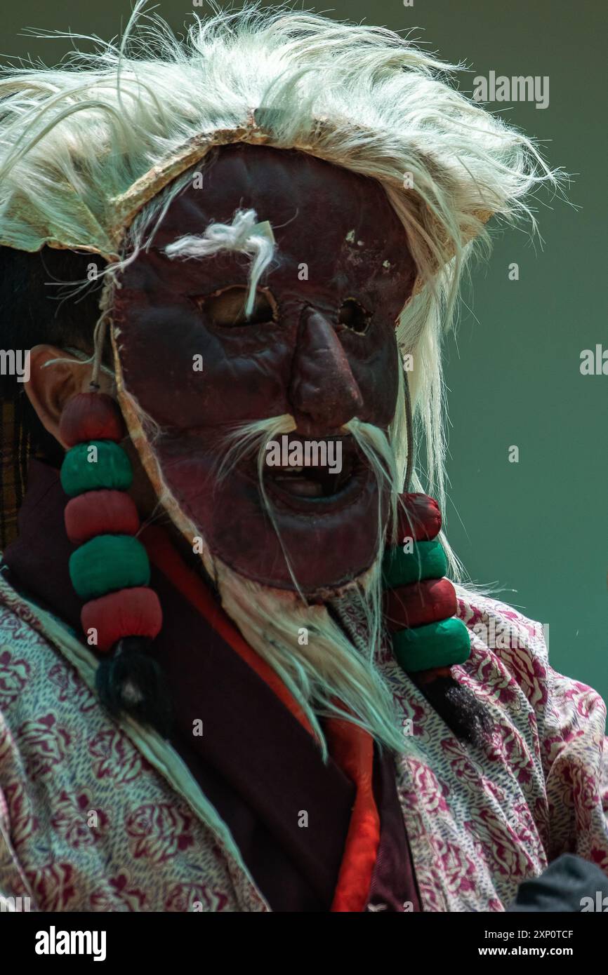 Porträt eines Mönchs, der eine Maske mit weißem Haar trägt und auf einem Festival in Ladakh steht. Stockfoto