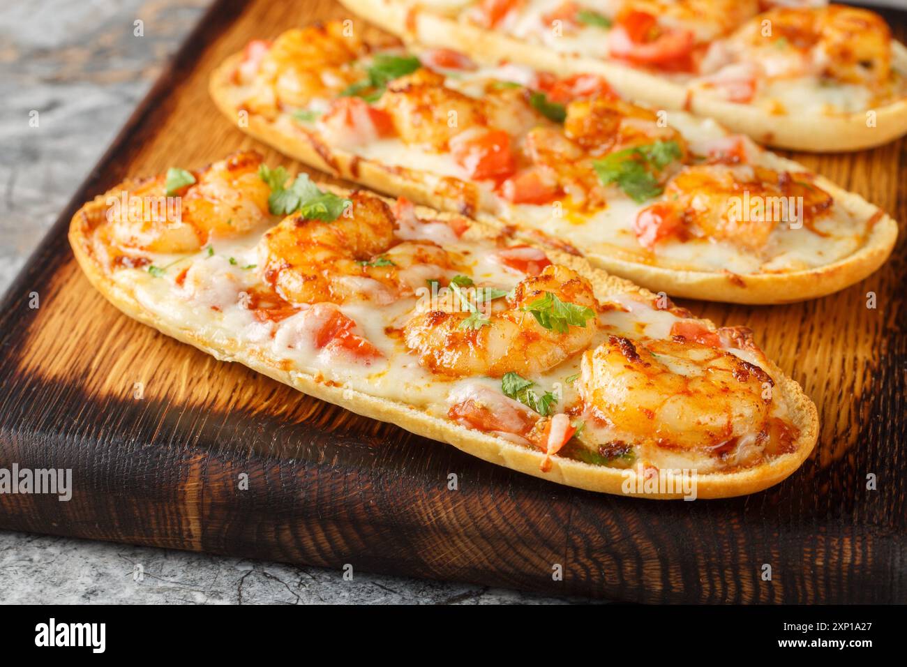 Shrimps Scampi Knoblauch Brotsandwiches mit Mozzarella, Tomaten und Petersilie auf dem Holzbrett auf dem Tisch. Horizontal Stockfoto