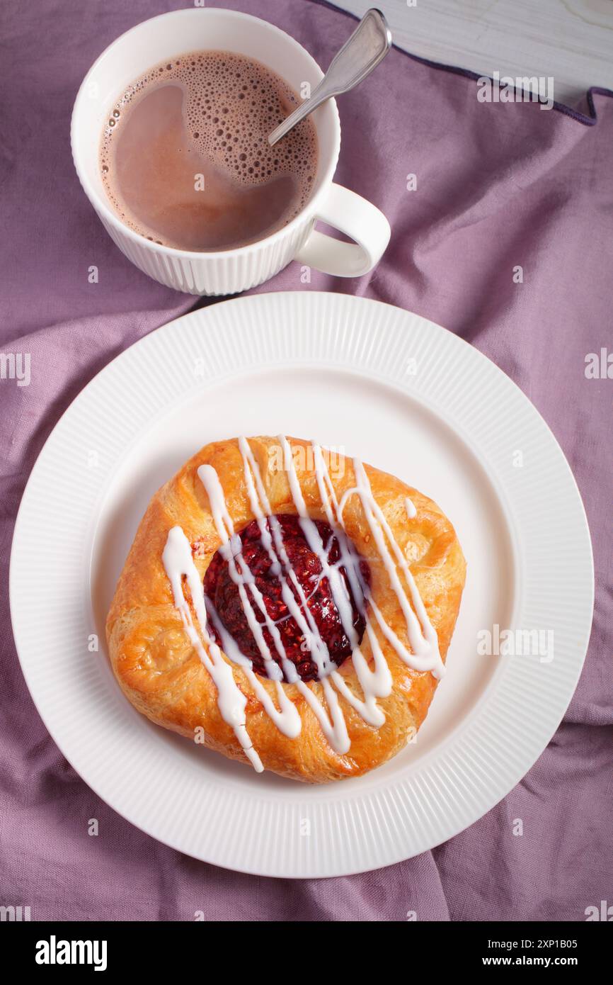 Dänisches Gebäck mit Himbeermarmelade und einer Tasse heißer Schokolade Stockfoto