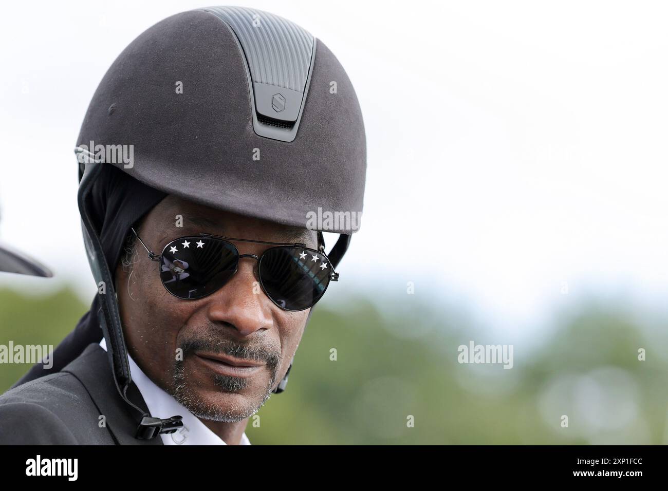 Versailles, Frankreich. August 2024. Olympia, Paris 2024, Pferdesport, Dressur, Team, im Finale trägt der US-Rapper Snoop Dogg einen Reithelm am Rande des Finales. Quelle: Rolf Vennenbernd/dpa/Alamy Live News Stockfoto