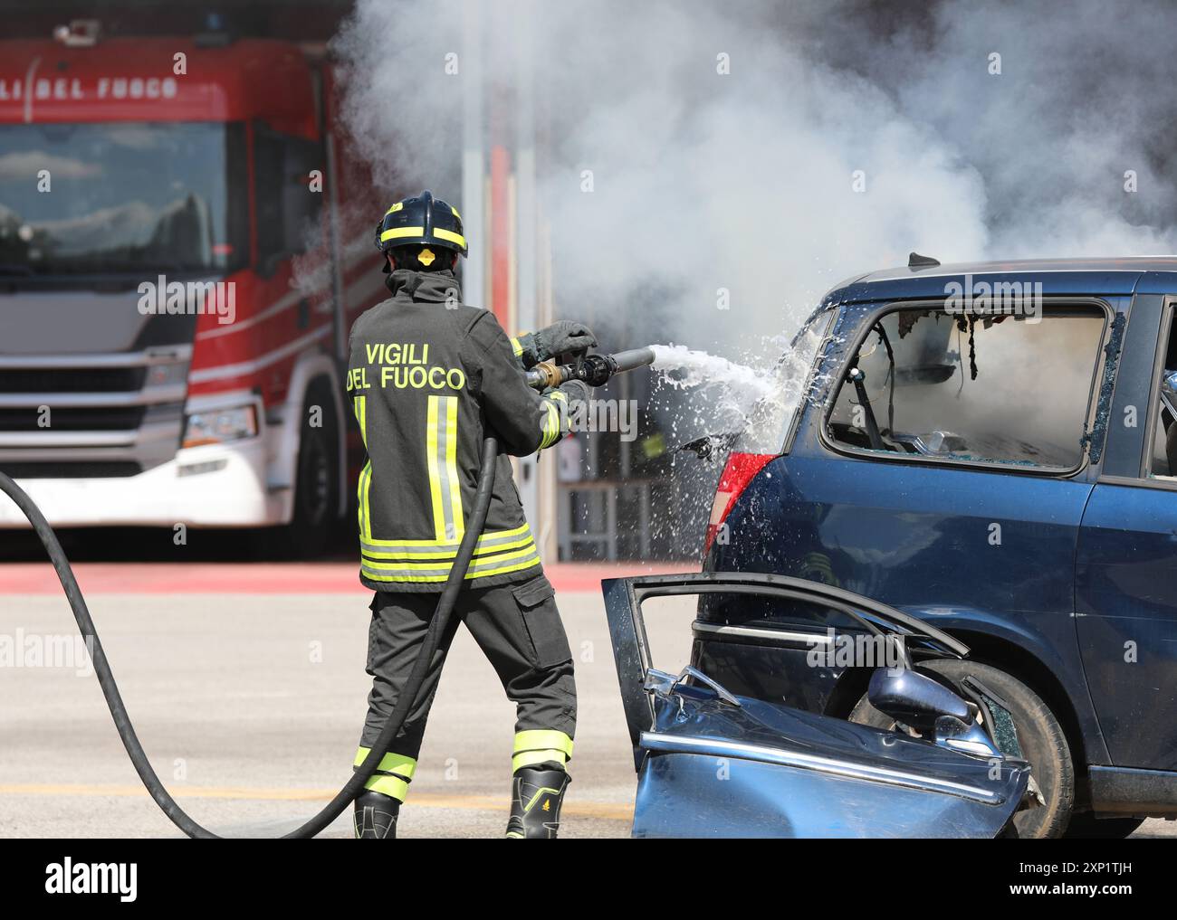 Vicenza, VI, Italien - 23. Mai 2024: Die italienische Feuerwehr sprüht Wasser und Löschmittel aus dem Schlauch, um das Feuer eines abgestürzten Autos zu löschen Stockfoto
