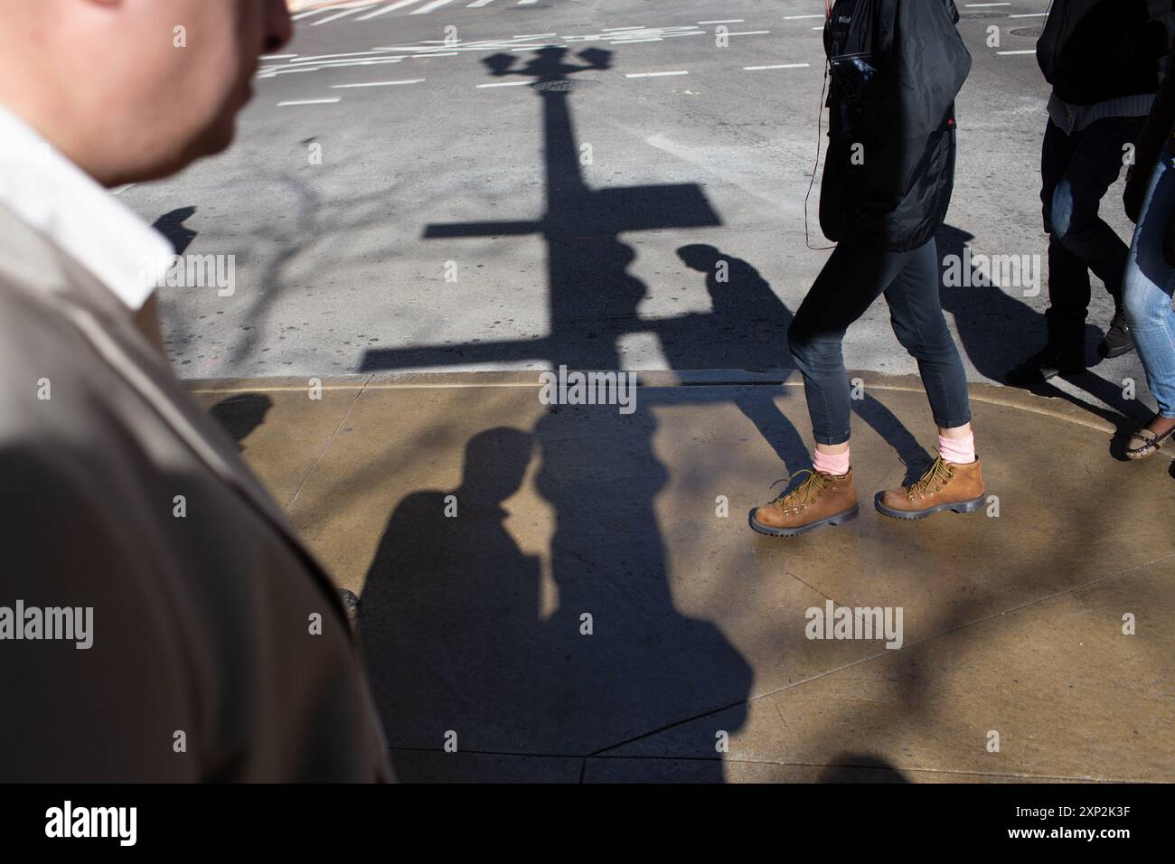 Urbane Straßenszene mit Fußgängern und Schatten, die Bewegung, Interaktion und Einfluss in einer geschäftigen Stadtumgebung symbolisieren. Stockfoto