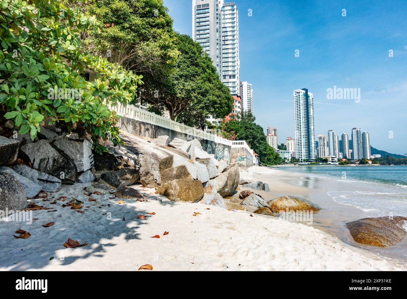 Ein Blick auf den Tanjing Tokong Strand in Penang, Malaysia, mit hohen, modernen Wolkenkratzern, Teil einer Stadtlandschaft im Hintergrund. Stockfoto