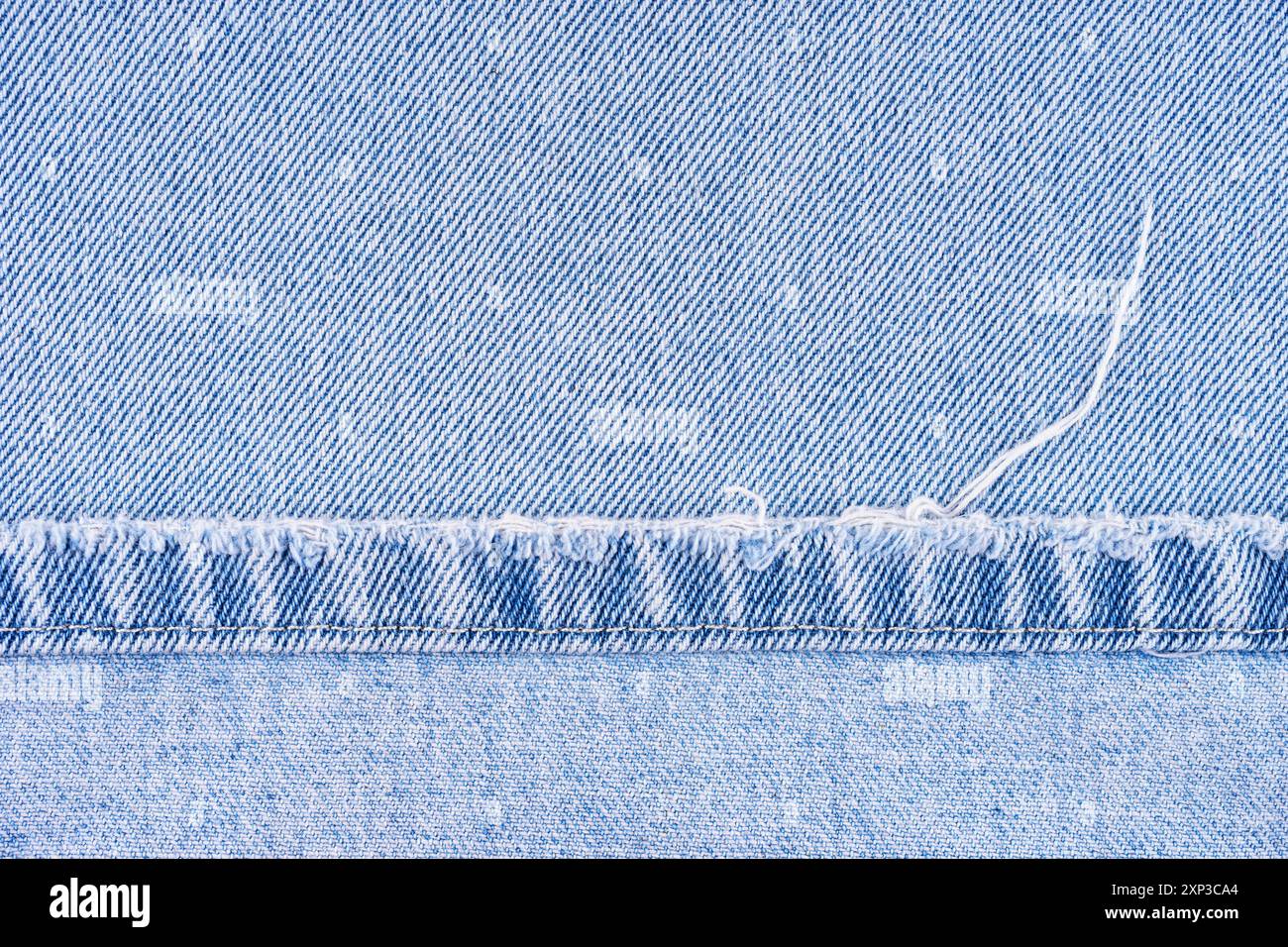 Blaue Jeans Hose mit schäbigem Rand auf jeansstoff Hintergrund, Nahaufnahme, Makro. Zerrissene Jeans stich, zerstört, zerrissen. Tapete, Hintergrund, Designdetails. Stockfoto