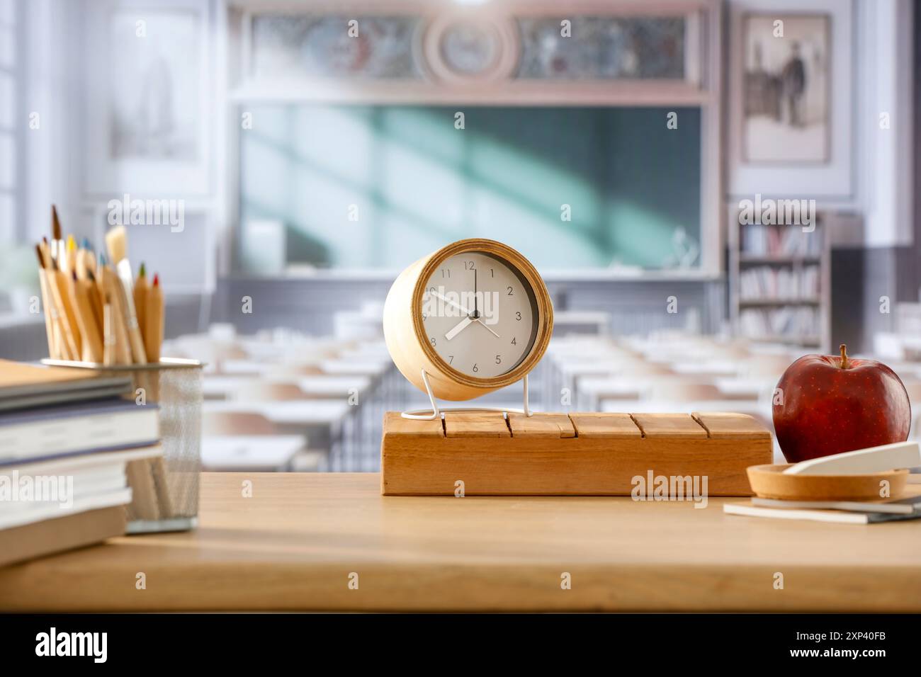 Schulsachen und Rucksack auf der Schulbank im Klassenzimmer. Verschwommener Hintergrund der Tafel an Wand und Fenster mit Sonnenlicht. Stockfoto