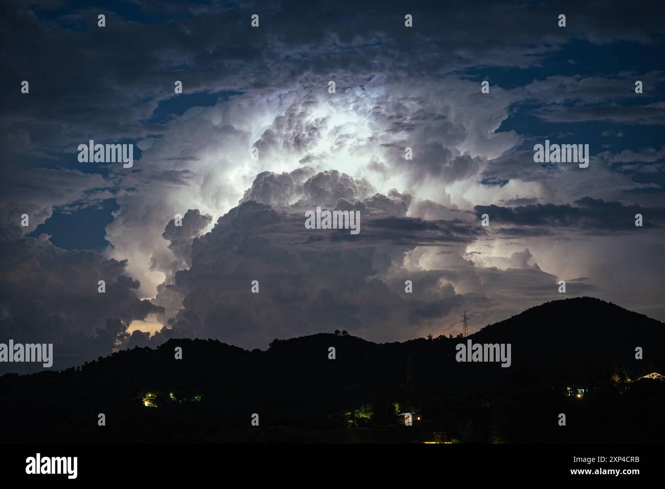 Eine Gewitterwolke über der nördlichen Toskana, Italien, wird nachts von innen durch Blitze beleuchtet Stockfoto