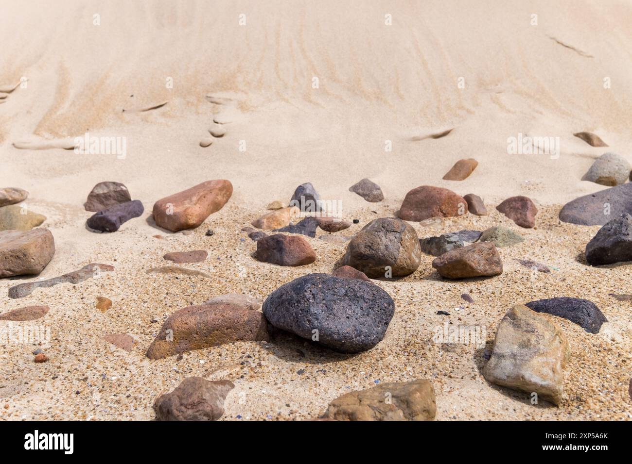 Felsen am Sandstrand mit großer Sanddünen-Kulisse Stockfoto
