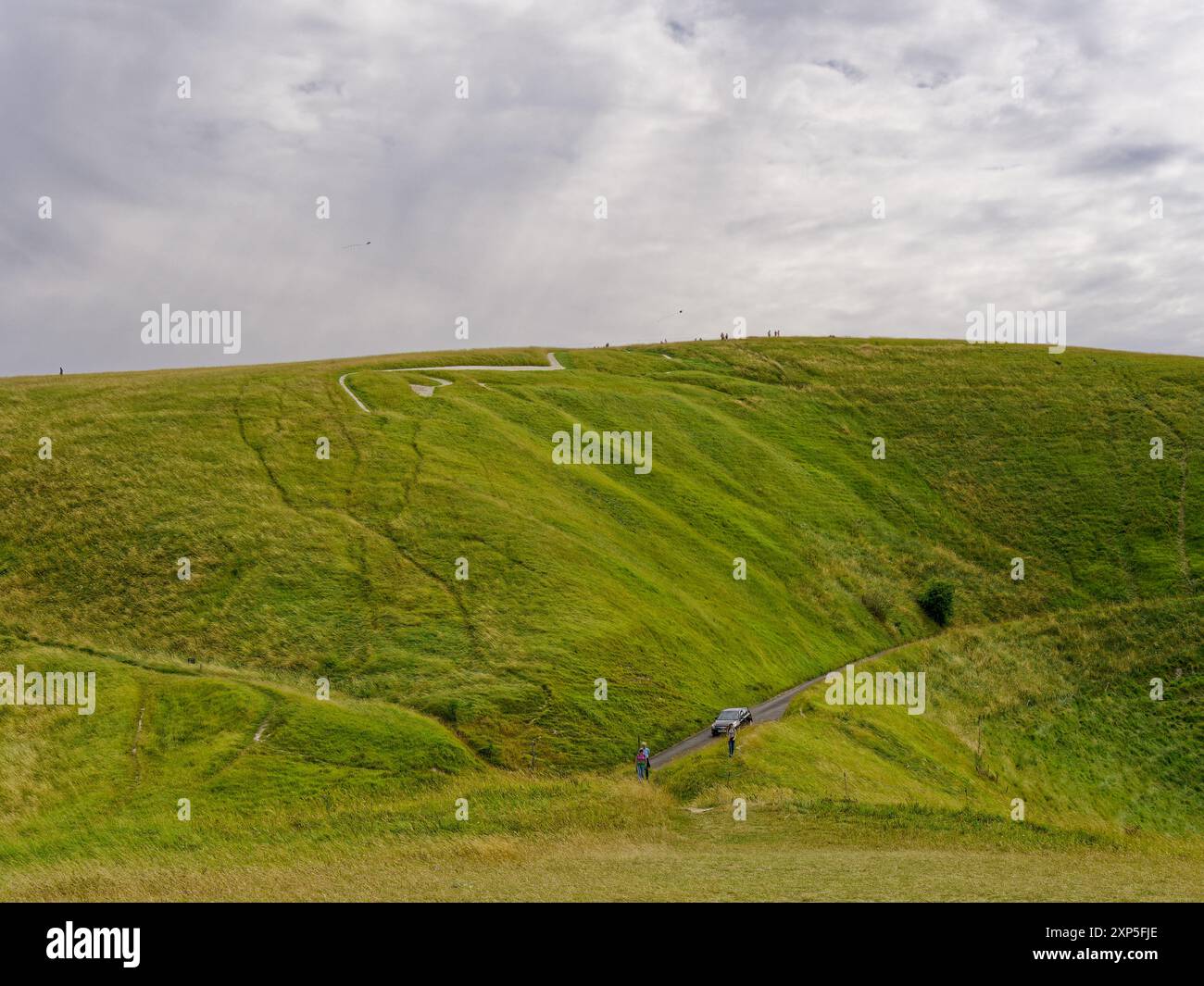 Uffington White Horse Hill Figur mit Touristen auf dem Gipfel und Spaziergängen entlang der Fußwege vom Dragon Hill in Uffington, Oxfordshire, England, Großbritannien Stockfoto