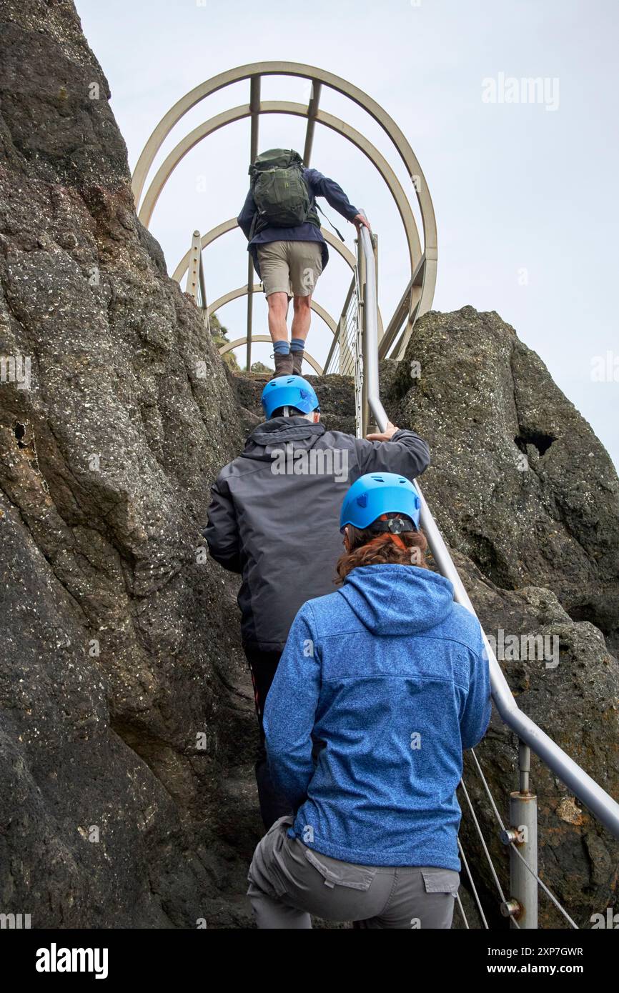 Der Reiseleiter führt Touristen entlang des Gobbins Coastal Walk in Richtung der Röhrenbrücke County antrim, Nordirland, großbritannien Stockfoto