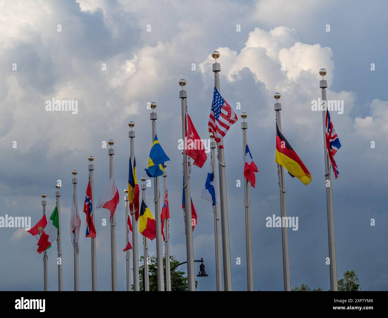 Farbenfrohe Fahnen aus aller Welt flattern majestätisch im Wind vor einem bewölkten Himmel vor dem berühmten Olympic Center im Zentrum von Lake Placid Stockfoto