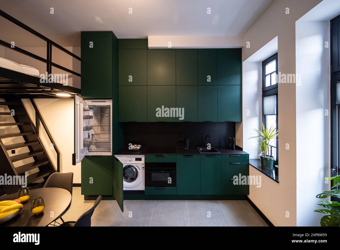 Modernes Studio-Apartment mit Zwischengeschoss-Schlafzimmer. Stilvolle Küche, die nahtlos mit einem gemütlichen Wohnzimmer verbunden ist, ideal für kleine Wohnräume. Klein und Mo Stockfoto