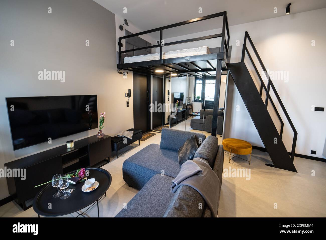 Modernes Studio-Apartment mit Zwischengeschoss-Schlafzimmer. Stilvolle Küche, die nahtlos mit einem gemütlichen Wohnzimmer verbunden ist, ideal für kleine Wohnräume. Klein und Mo Stockfoto