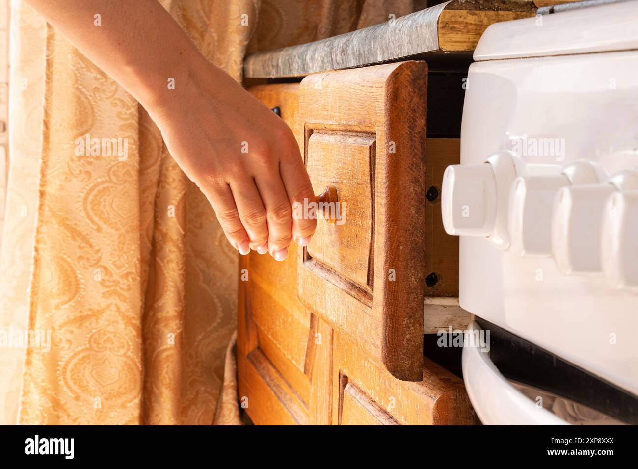 Weibliche Hand öffnet braunen alten Küchenschrank in der Küche in der Wohnung, Küchenmöbel Stockfoto