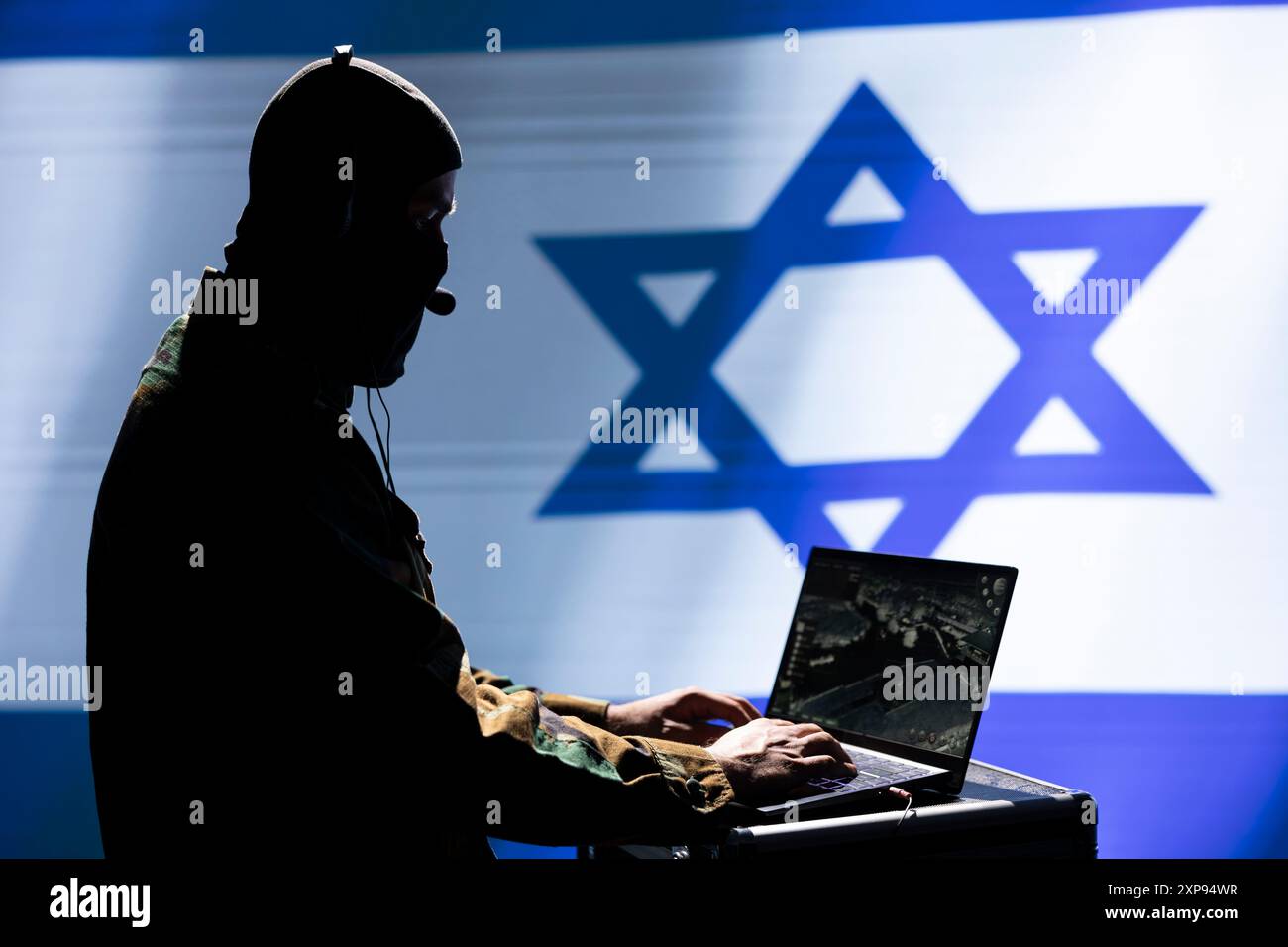 Der Mossad-Agent nutzt Radargeräte, um Überwachungsdaten zu analysieren. Er steht isoliert über dem Hintergrund der israelischen Flagge. Geheimdienstspion beendet Mission während geopolitischer Operation Stockfoto