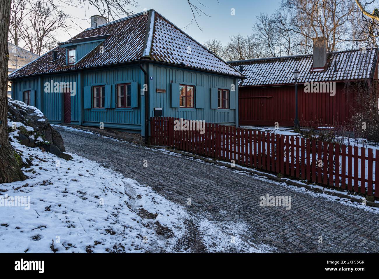 Traditionelles schwedisches blaues Holzhaus in einer verschneiten Straße im Gathenhielm Cultural Reserve, Göteborg Stockfoto