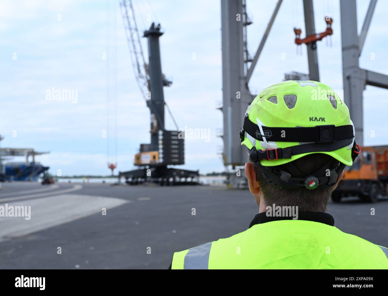 Bremse, Deutschland. August 2024. Ein Hafenarbeiter blickt auf den Ladekran. Ab 6 Uhr morgens sollen zwei Elektrolokomotiven der Rail Cargo Carrier Germany GmbH (RCC) mit Kranen auf die Lastkahn „ELKA“ gehoben und auf dem Seeweg transportiert werden. Quelle: Lars Penning/dpa/Alamy Live News Stockfoto