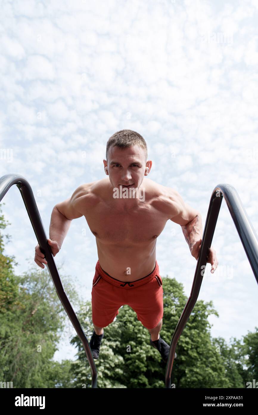 Ein Mann, der im Park Einbrüche an parallelen Leisten durchführt Stockfoto