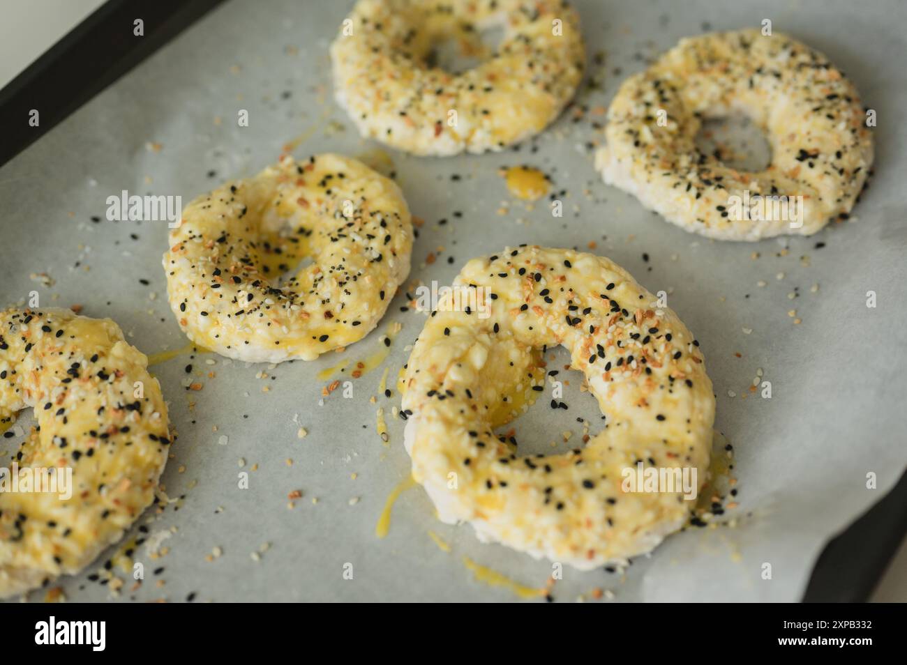 Hausgemachte Hüttenkäse-Bagels auf Pergamentpapier, fertig zum Backen Stockfoto