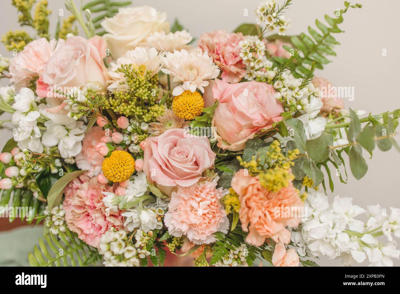 Elegantes Blumenarrangement mit pastellfarbenen Rosen und Farnen in einer Vase Stockfoto