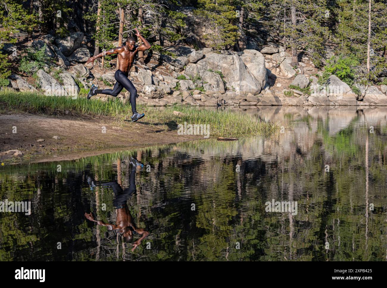Springender Mann in der Nähe des Wassers während des Traillaufs Stockfoto