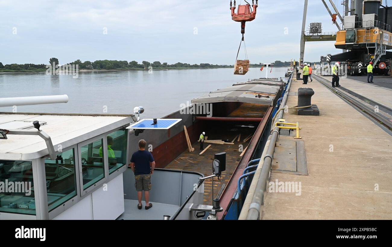 Bremse, Deutschland. August 2024. Hafenarbeiter schauen sich das Ladegerät des mobilen Hafenkrans an. Zwei strängige Elektrolokomotiven der Rail Cargo Carrier Germany GmbH (RCC) sollen mit zwei Hafenmobilkranen auf den Lastkahn „ELKA“ gehoben und auf dem Seeweg transportiert werden, wahrscheinlich um 6 Uhr am 7. August 2024. Die Strecke der Lokomotiven wurde durch einen Brückenbrand abgeschnitten. Quelle: Lars Penning/dpa/Alamy Live News Stockfoto