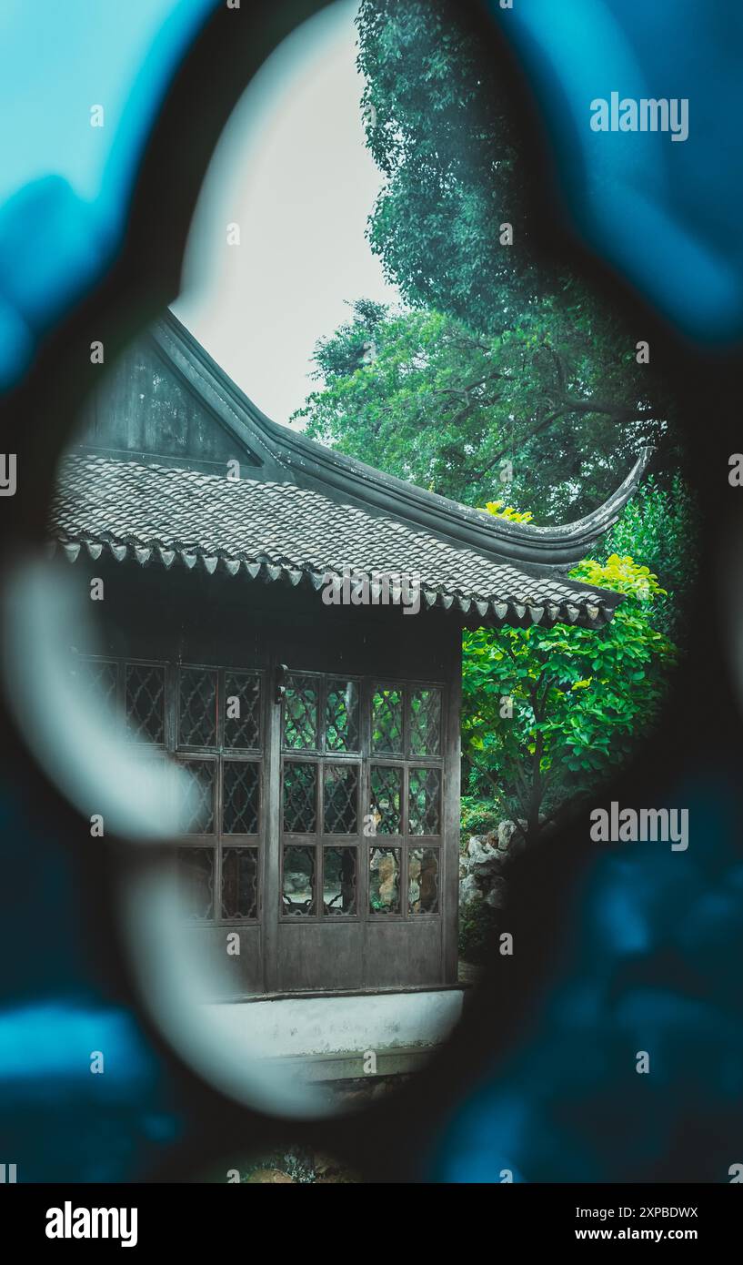 Blick auf einen chinesischen Gartenpavillon durch einen blau gemusterten Rahmen. Stockfoto